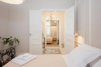 a white bedroom with a bed and a mirror at Villa Kalliopi in Chania Town