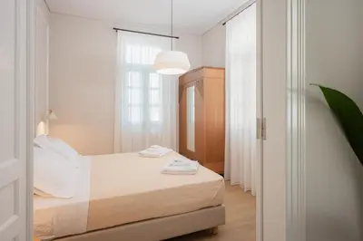 a white bedroom with a bed and a window at Villa Kalliopi in Chania Town