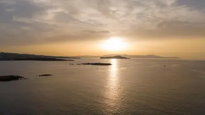 a sunset over a body of water with the sun setting at Lazareta 3 in Chania Town