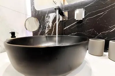 a black bowl with water pouring into a bathroom sink at Argiros House in Chania Town