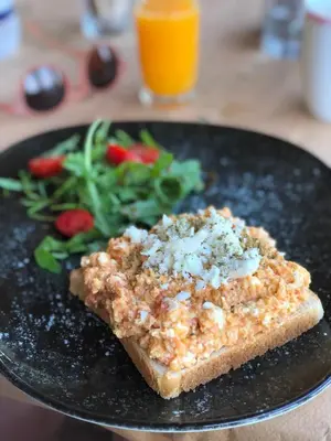 a black plate with a piece of bread and a salad at Glykeria Hotel in Elafonisi