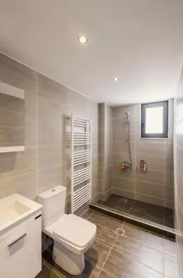 a bathroom with a white toilet and a shower at Kayzo Luxury Apartment With Pool in Tavronitis