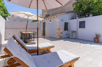 a patio with chairs and an umbrella and a table at Myra city House in Chania Town