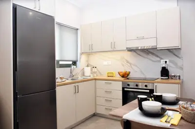 a kitchen with white cabinets and a stainless steel refrigerator at Olgas cozy home in Chania Town