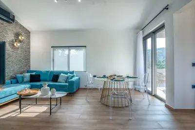 a living room with a blue couch and tables at Alyona Villas - Villa Lona in Skinés