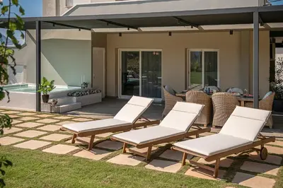 a patio with white chairs and a pool at HappyHouse Villa in Kissamos