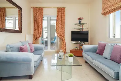 a living room with two blue couches and a tv at Kostoula's House Beachfront in Stalos
