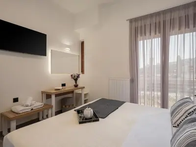 a white bedroom with a bed and a window at Elia Seaside Deluxe Apartment in Chania Town