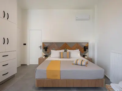a bedroom with a large bed with striped pillows at Elia Seaside Deluxe Apartment in Chania Town