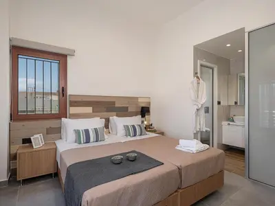 a bedroom with a large bed and a bathroom at Elia Seaside Deluxe Apartment in Chania Town