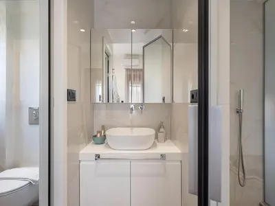 a white bathroom with a sink and a mirror at Elia Seaside Deluxe Apartment in Chania Town