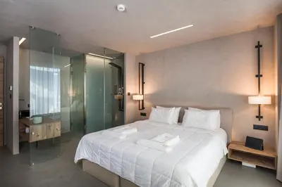 a bedroom with a large white bed and a glass shower at Icarus Hotel in Kalamaki Chanion