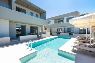 a house with a swimming pool with chairs and an umbrella at Heliades Residence in Kounoupidhianá