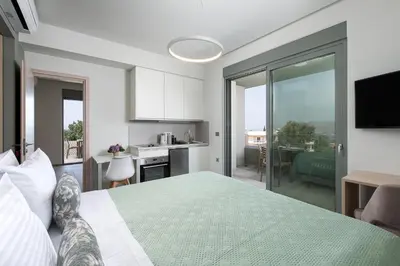 a bedroom with a large bed and a kitchen at Heliades Residence in Kounoupidhianá