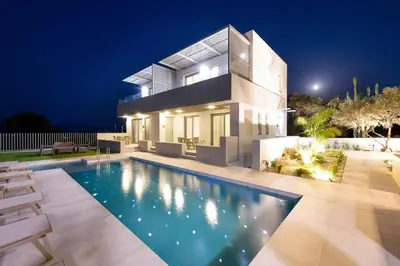 a house with a swimming pool at night at Heliades Residence in Kounoupidhianá