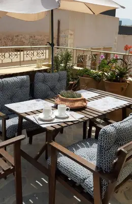 a wooden table and chairs on a balcony with an umbrella at Myron House in Chania Town