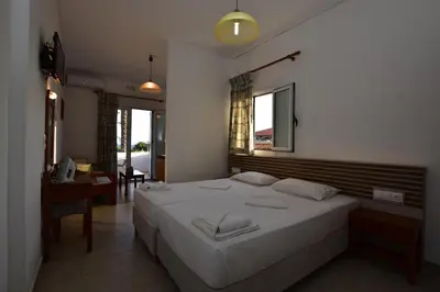 a bedroom with a large white bed and a desk at Morpheas Rooms in Palaiochóra