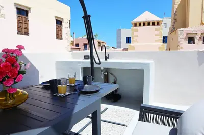 a table on a balcony with a vase of flowers at Porto 57 in Chania Town