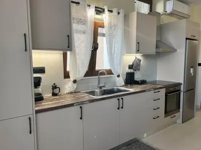 a kitchen with white cabinets and a sink and a window at Perion stone apartment sea front in Kolymvari
