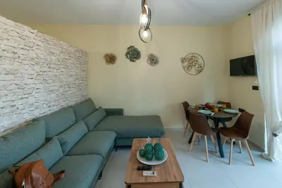 a living room with a blue couch and a table at Perion stone apartment sea front in Kolymvari