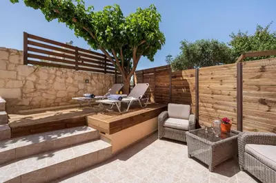 a patio with a fence and two chairs and a table at Anna Boutique Apartment in Kato Daratso