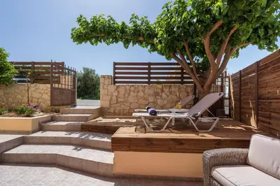 a patio with a table and a tree and stairs at Anna Boutique Apartment in Kato Daratso