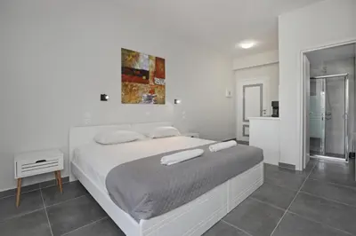 a white bedroom with a large bed and a bathroom at El Greco Studios in Agia Marina Nea Kydonias