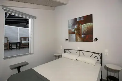 a white bedroom with a bed and a window at El Greco Studios in Agia Marina Nea Kydonias