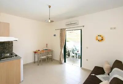 a kitchen and living room with a couch and a table at Aptera Paradise With Sea View in Megála Khoráfia