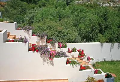 a white garden with flowers on a white wall at Aptera Paradise With Sea View in Megála Khoráfia