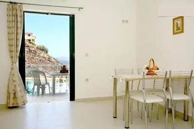 a dining room with a table and chairs and a balcony at Aptera Paradise With Sea View in Megála Khoráfia