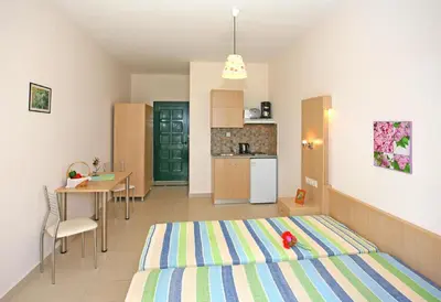 a room with a bed and a table and a kitchen at Aptera Paradise With Sea View in Megála Khoráfia