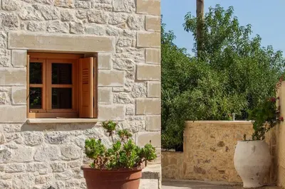 a stone building with a window and two potted plants at Amygdalia Traditional House in Chania Town