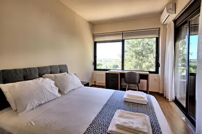 a bedroom with a bed and a desk and a window at Iris by PosarelliVillas in Kounoupidhianá