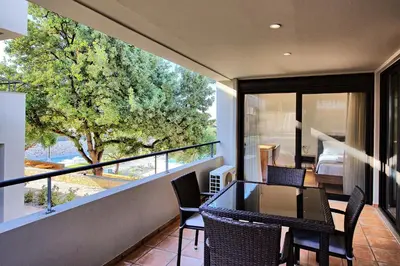 a balcony with a table and chairs and a large window at Dioni by PosarelliVillas in Kounoupidhianá