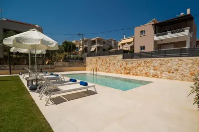 a villa with a swimming pool and an umbrella at Aelia by PosarelliVillas in Kounoupidhianá