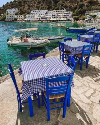 a table and chairs with a boat in the water at Erofili central apartment in Chania Town