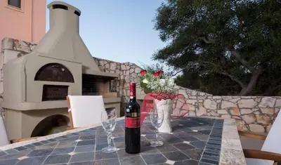 a bottle of wine sitting on a table with glasses at Villa Majestic Crete heated pool and sauna in Megála Khoráfia