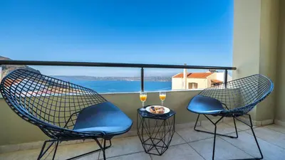 a balcony with two chairs and two glasses of wine at Villa Majestic Crete heated pool and sauna in Megála Khoráfia