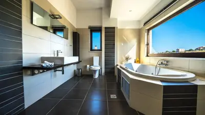 a bathroom with a tub and a sink and a toilet at Villa Majestic Crete heated pool and sauna in Megála Khoráfia
