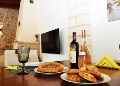 a table with two plates of food and a bottle of wine at ESTIA stone house in Vrísai