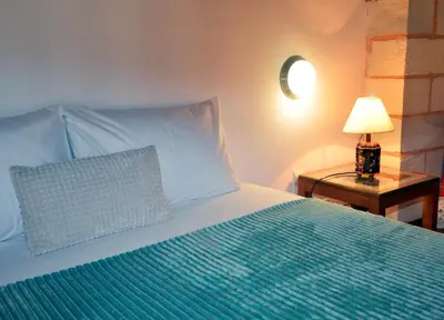 a bed with a pillow and a lamp on a table at ESTIA stone house in Vrísai