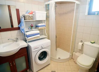 a bathroom with a washing machine and a shower at ESTIA stone house in Vrísai