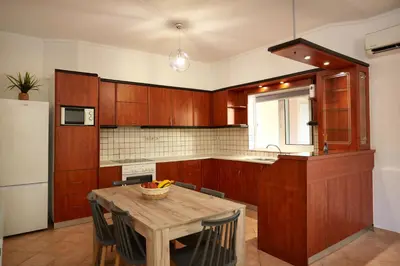 a kitchen with wooden cabinets and a wooden table at Sylvias Stylish Apartment in Chania Town