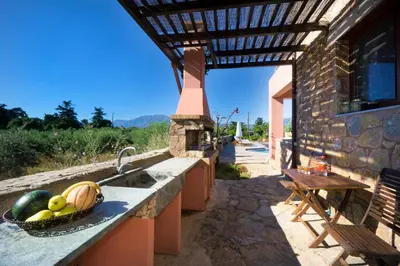an outdoor kitchen with a sink and a table at Villa Litsarda in Litsárdha