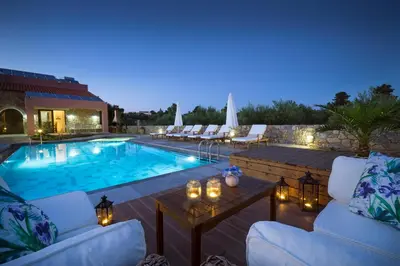 a patio with a pool and chairs and a table at Villa Litsarda in Litsárdha