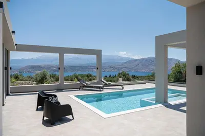 a house with a swimming pool with mountains in the background at Sunny Vacay Villa in Stérnai