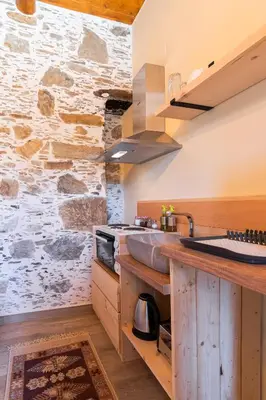 a kitchen with a sink and a stone wall at Plagia Rooms in Kissamos