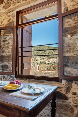 a table with two plates on it in front of a window at Plagia Rooms in Kissamos
