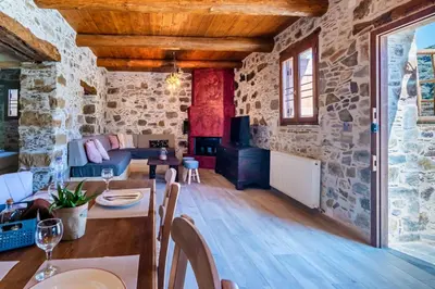 a living room with stone walls and wooden ceilings at Plagia Rooms in Kissamos